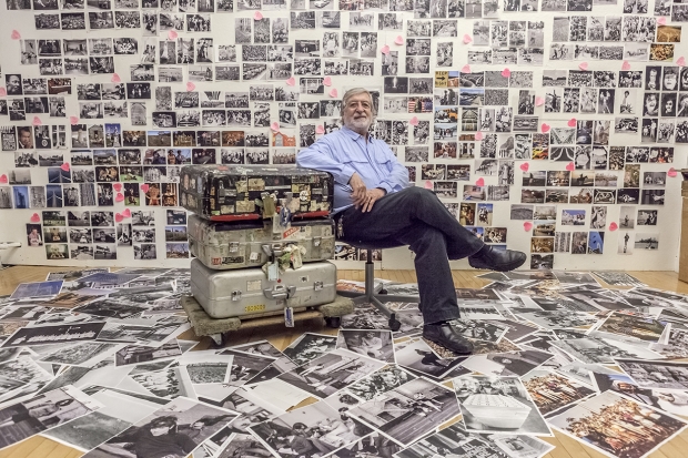 June 25, 2013. Manhattan, New York. Jean-Pierre Laffont in front of 'Photographer's Paradise' book wall. He sits next to his suitcases that moved around the world with him. Photograph by Sam Matamoros.